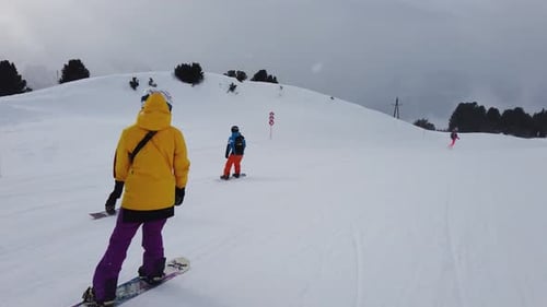 girl in yellow snowboarding in alps YL