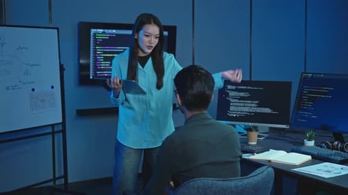 Female Developer Presenting At Whiteboard To Colleague