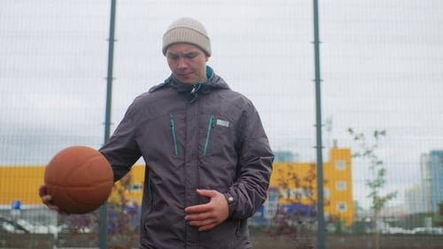Urbaner Athlet bereitet sich auf das Spiel vor. Männlicher Spieler trainiert Basketball inmitten eines athletischen Mannes im Stadtbild