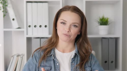 A Smiling Woman in Stylish Casual Attire Poses Confidently Against a Bright Office Background