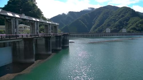 Pan view of a lake over a dam with emerald waters on a bright, sunny day