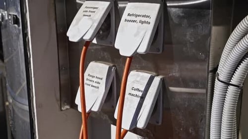 Close-up of labelled power outlets on a mobile cafe cart, with cables supplying electricity to