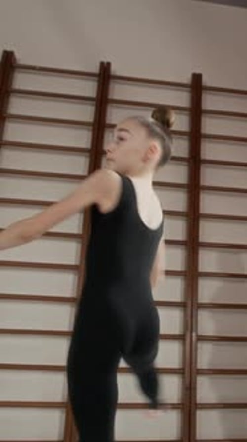 Graceful Girl in Black Activewear Outstretching Arms and Whirling in Gym