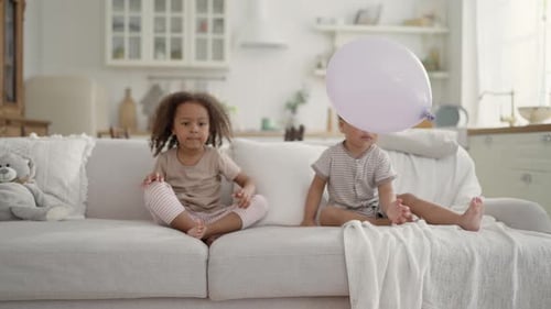 Kids Playing with Balloons on Sofa