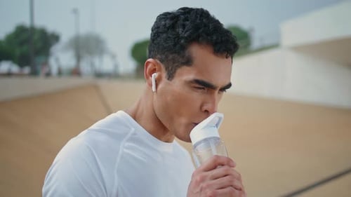 Athletic Man Drinking Water at Outdoor Venue