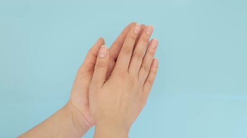 Frau klatscht beim Feiern und Applaus bei der Handgeste isoliert in einem blauen Studio