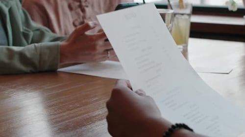Group of Friends in Restaurant Looking at Phone, Communicating and Choosing Food