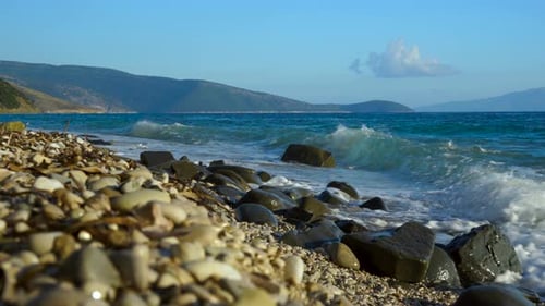 Rocks and pebbles on beach washed by sea waves on beautiful seascape on a summer day in Mediterranea