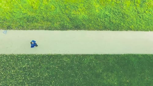 Young Athlete Running in Green Nature on Asphalt Path Action