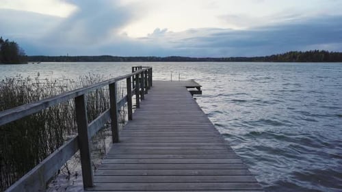 Leerer Holzsteg an einem See an einem windigen Herbstabend