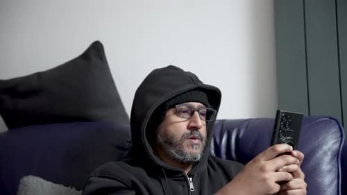 Man Sitting on Couch Using Mobile Phone Indoors