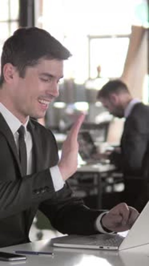 Man in Suit Video Conferencing on Laptop at Workplace