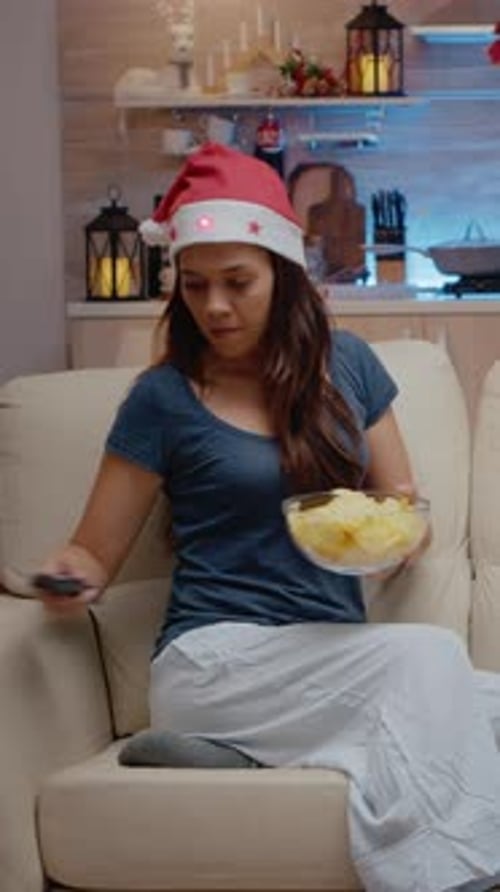 Vertical Video Festive Woman Watching Television and Eating Chips From Bowl