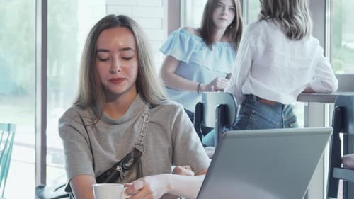 Cheerful Young Woman Immersed in Her Laptop at a Trendy Coffee Shop