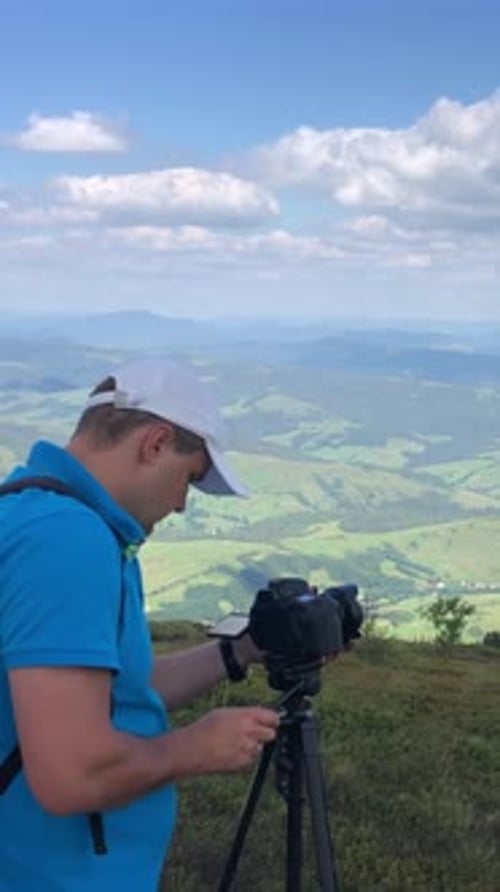 A Photographer is Setting Up a Camera on a Tripod to Capture Stunning Mountain Landscapes and Scenic