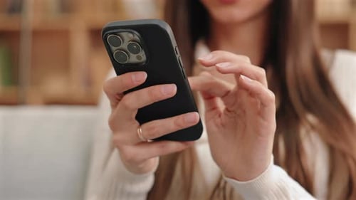 Close View of Caucasian Woman Wearing Ring Holding Smartphone Indoors and Tapping Screen with