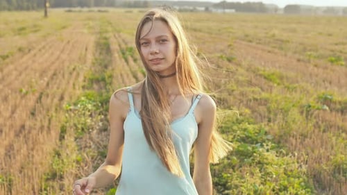 Portrait of a 16 Year Old Girl Standing in the Field at Dusk with Long Hair and a Blue Dress