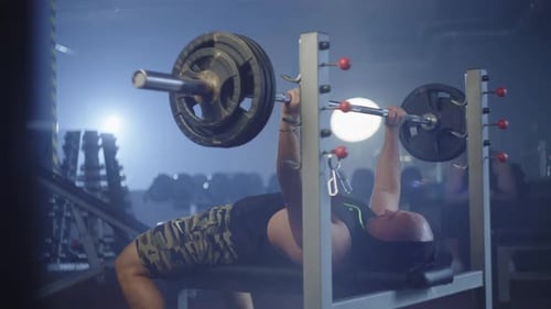 Athletischer kaukasischer Mann schwingt seine Arme, während er im Fitnessstudio eine Langhantel hebt