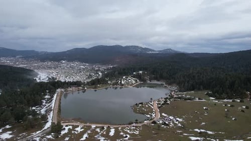 Snowy Village and Lake with Dense Forest in Winter