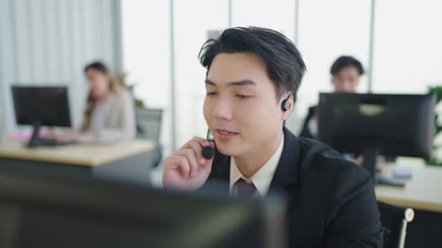 Asian man is customer support agent, call center works on desktop computer