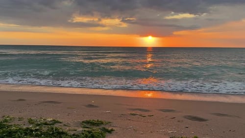 Faszinierender Sonnenuntergang über dem ruhigen Meer mit sanften Wellen am Strand
