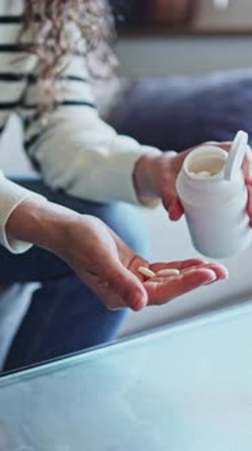 Woman taking medication from pill bottle
