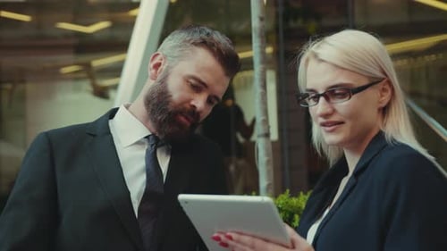 Business Colleagues Reviewing Tablet Outside Office Building