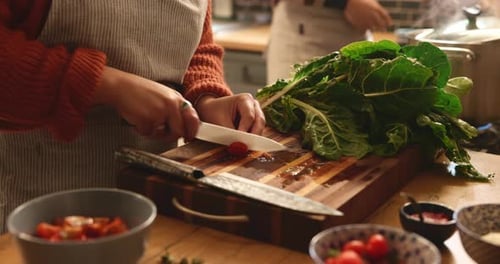 Person Slicing Tomatoes in Bright Kitchen Setting