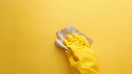 Hand Cleaning a Yellow Surface with Cloth