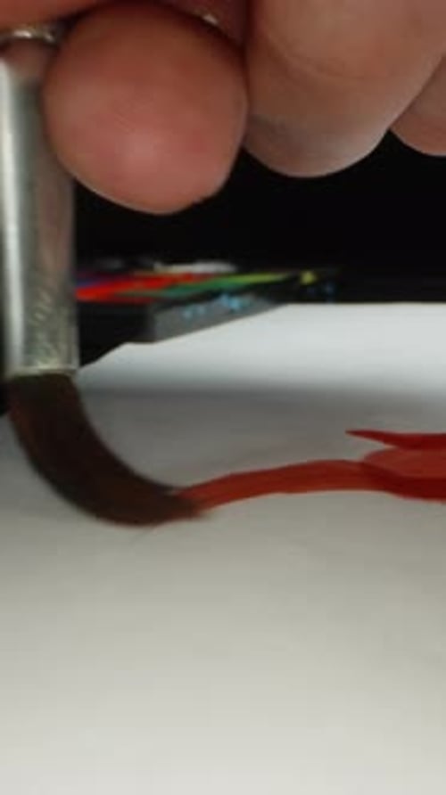 Vertikales Video. Der Künstler malt mit einem Pinsel in roter Farbe auf Papier, das nass wird und sich kräuselt
.