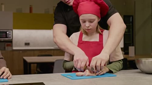 Professioneller Koch bringt Mädchen im Kochkurs das Schneiden von Hühnchen bei