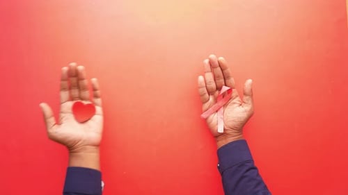Hand Holding Red HIV Ribbon Top Down