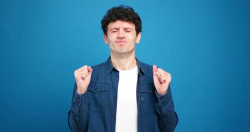 Hopeful man crossing fingers against blue background