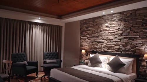 Hotel Room Interior - Luxurious Hotel Suite With Comfortable Bed Against Stone Accent Wall And Two T