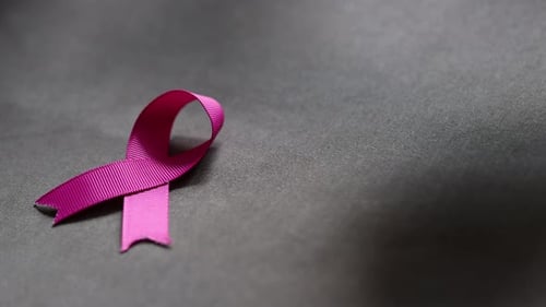 Pink Ribbon Placed on Gray Fabric, Close Up