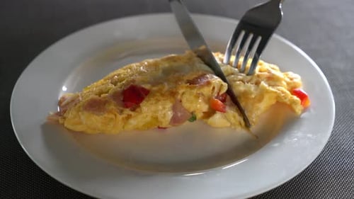 Knife and Fork Cutting Into Golden Omelet