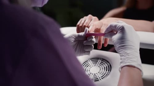 Manicurist Files Client's Nails in Nail Salon