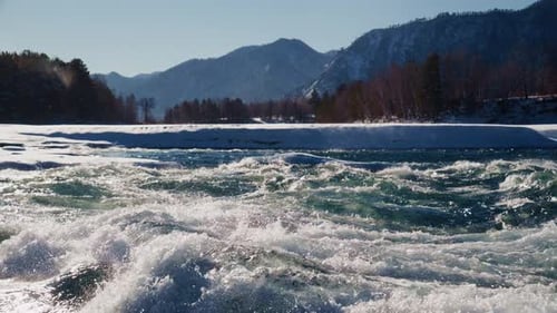 Experience the Dynamic River Rapids Flowing Vigorously Through Stunning Snowy Mountain Regions and