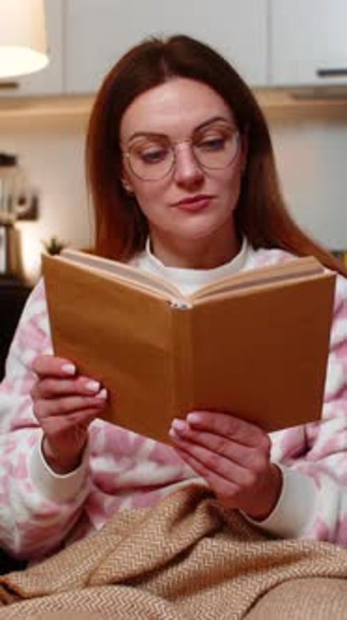 Erwachsene Frau mit Brille liest am Abend gerne ihren Lieblingsroman Kuschelig unter der Decke Relax Calm Cozy