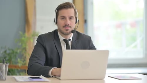Businessman with Headset Looking toward Camera in Call Center