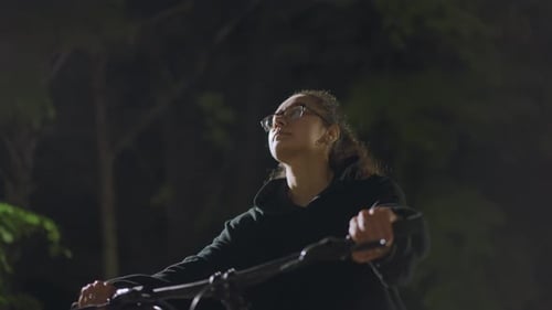 Woman on scooter at night with street lights