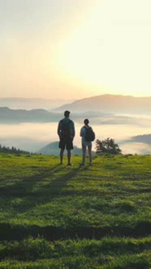 A Man and a Woman on Top of a Mountain Meet the Sunrise Morning Fog in a Mountain Valley Beautiful