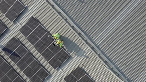 Vue de dessus ou vue par Drone de deux techniciens utilisant un ordinateur portable et une tablette pour vérifier et entretenir