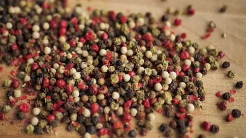 Mixed Peppercorns Being Poured on Wood Surface