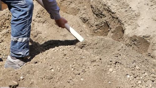 Using a Green Shovel a Person is Digging in the Soil