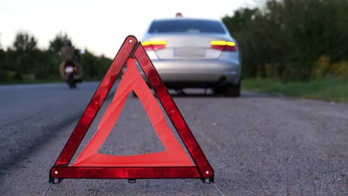 Broken Silver Luxury Car Emergency Accident Man Driver Installing Red Triangle Stop Sign on Road