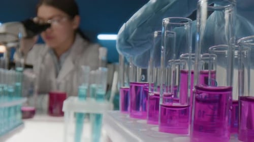 Scientist Examining Sample Under Microscope in Lab