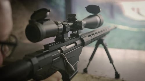 Shooter firing sniper rifle on shooting range, close up on weapon