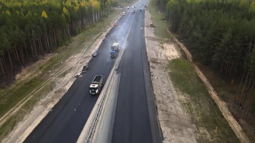 Road machinery repairing the highway. Dump truck with asphalt is moving slowly