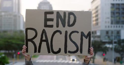 Shot of a unrecognizable woman protesting outside in the city